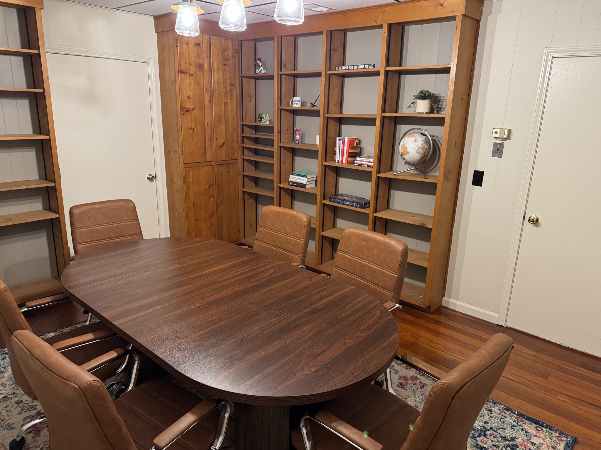 Hutchinson Yard meeting room with an oval wooden table, brown chairs, and built-in bookshelves